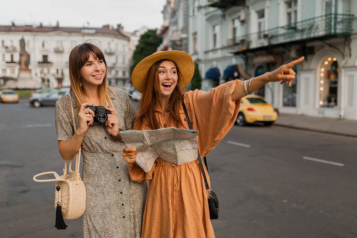 stylish-young-women-traveling-together-europe-dressed-spring-trendy-dresses-accessories-min
